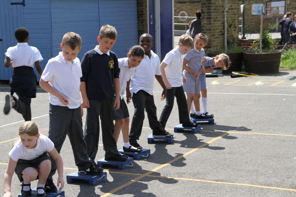 Key Stage 1 & key stage 2 students on blue Stepping Stones team building activity