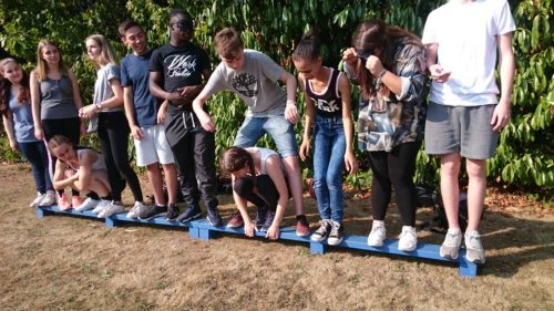 Children balancing on beam team building activity