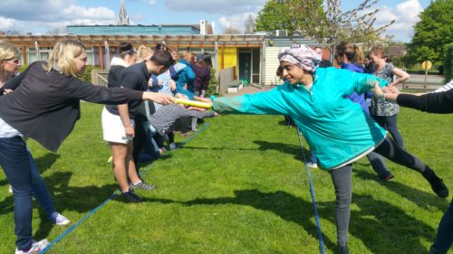 School staff reaching for baton team building game