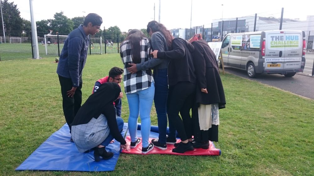 Teenagers holding onto each other for support during team building game on carpets