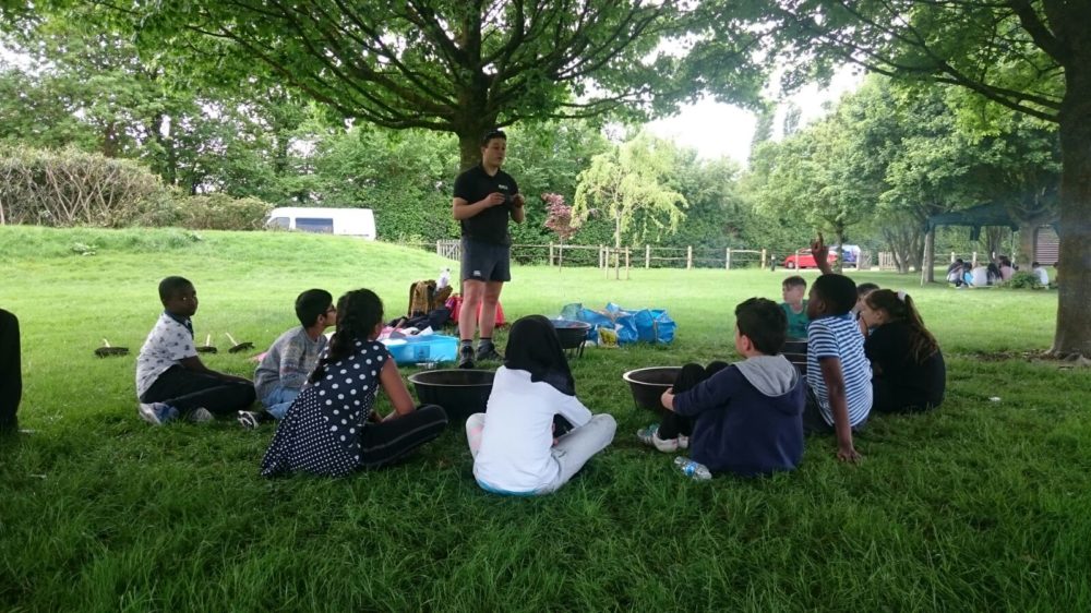 Young children sit in a circle listening to instructor